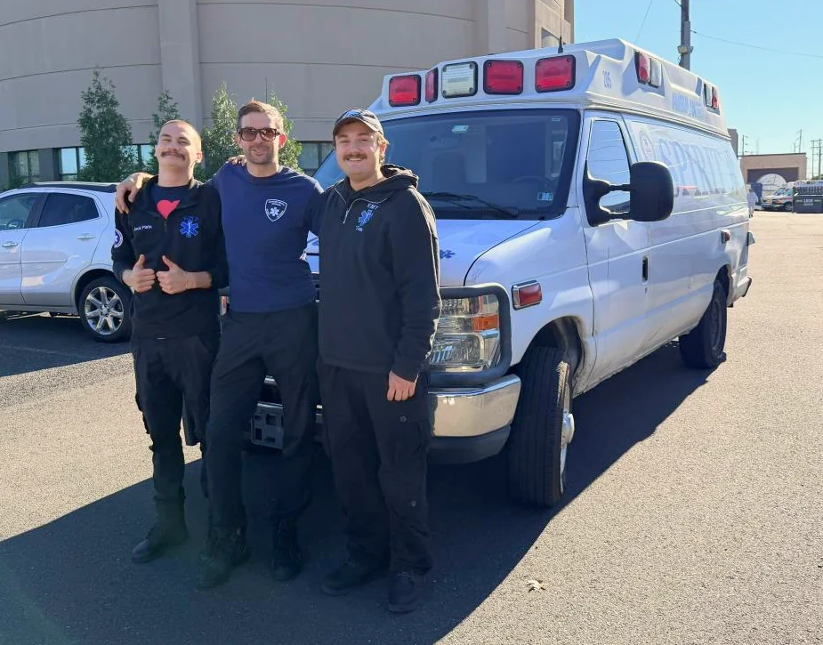 Three Spirit Ambulance team members standing in front of a Spirit ambulance.